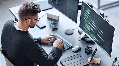 Mitarbeiter sitzt am Computer und programmiert