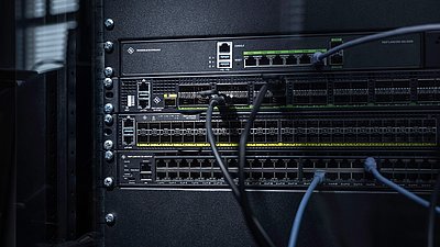 Trois switches montés en rack avec câbles : Core Switch R&S®LANCOM CS-8132F, Aggregation Switch R&S®LANCOM YS-7154CF et Access Switch R&S®LANCOM XS-4554XUP