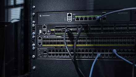 Drei R&S®LANCOM Switches eingebaut im Rack mit Kabeln: Core Switch R&S®LANCOM CS-8132F, Aggregation Switch R&S®LANCOM YS-7154CF und Access Switch R&S®LANCOM XS-4554XUP