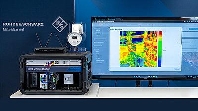 KRITIS-Demonstrator-Koffer mit Netzwerktechnik neben einem Monitor mit Wärmebild einer Industrieanlage.