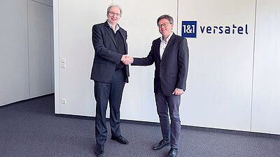 Ralf Koenzen, Gründer LANCOm Systems (heute Rohde & Schwarz Networks and Cybersecurity) (l.) und Dr. Sören Trebst, CEO, 1&1 Versatel geben sich nach Vertragsunterzeichnung die Hand.