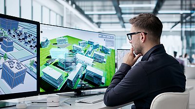 IT specialist monitors digital building models on multiple screens for highly secure network solutions.