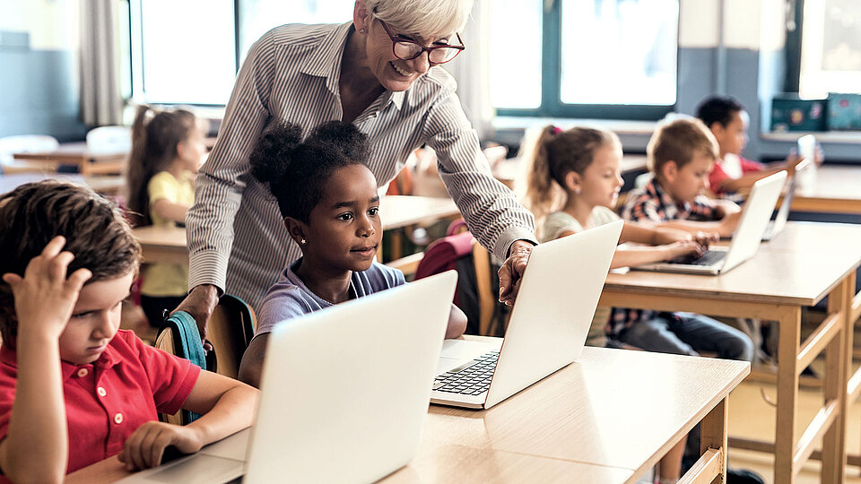 Lehrperson und Schulkinder im digital gestützten Unterricht