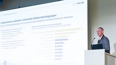 Uwe Greunke steht hinter einem Rednerpult und hält auf der Messe „Digitaler Staat 2024“ einen Vortrag über die veränderten Rahmenbedingungen für Unternehmen