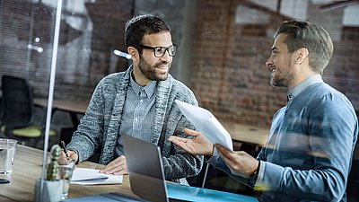 Deux collègues masculins discutent joyeusement au bureau.