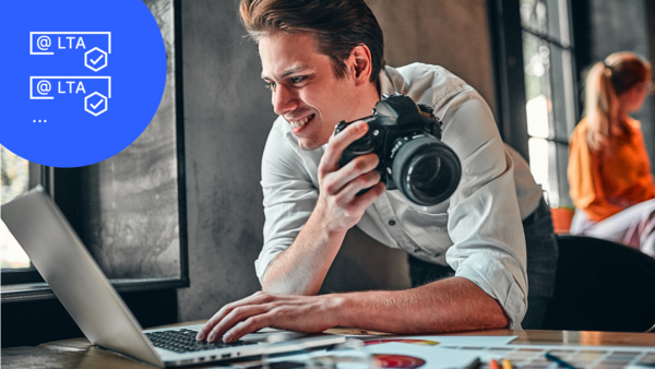 Mann mit Kamera schaut auf Laptop mit LTA Icon