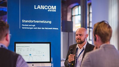 LANCOM Experten halten am Messestand einen Vortrag