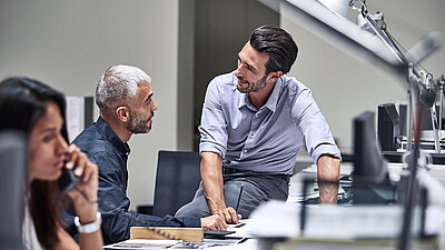 Photo: Colleagues talking at a desk