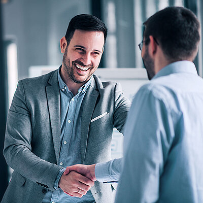 Two men in suits shake hands in a spirit of partnership