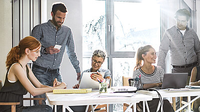 Personen diskutieren an einem Schreibtisch