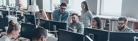 Group of young support staff work with commitment and good humor in open-plan office
